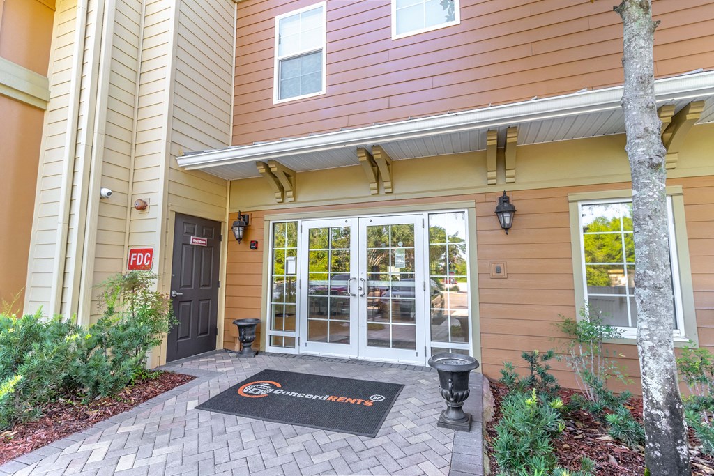 the entrance to a building with glass doors and a welcome mat in front of it