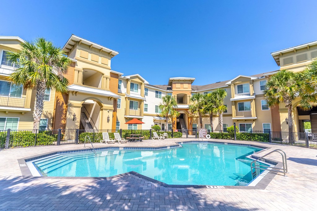 a swimming pool with palm trees in front of a building