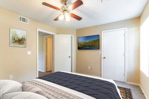 the master bedroom has a large bed and a ceiling fan