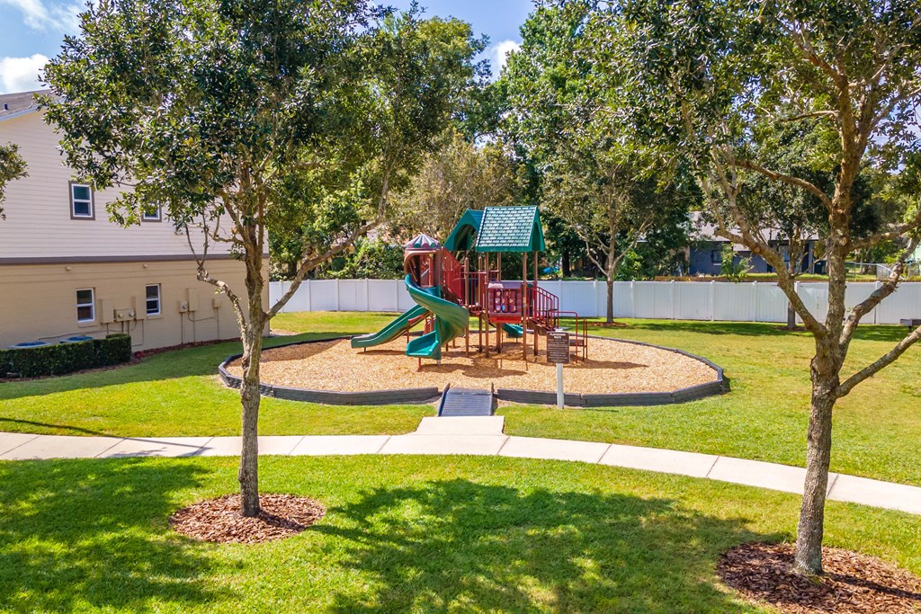 a playground with a slide in the middle of a grassy area