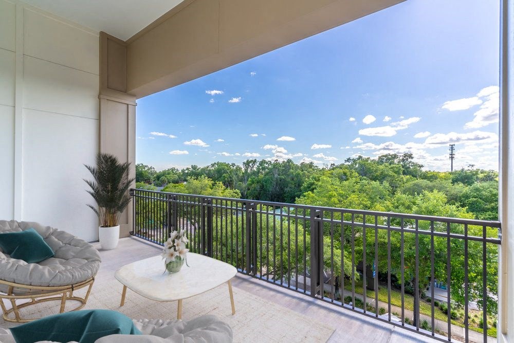a living room with a balcony and a view of trees