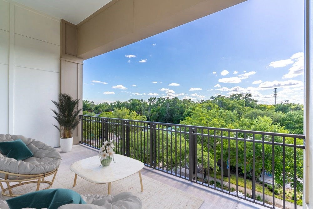a living room with a balcony and a view of trees