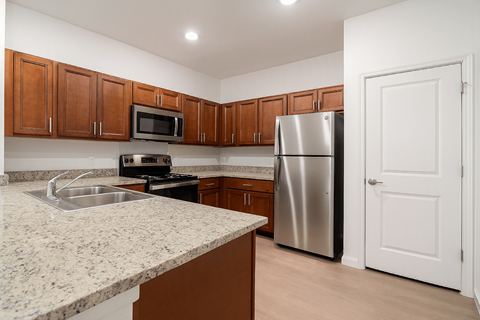 A kitchen with brown cabinets and a granite countertop.