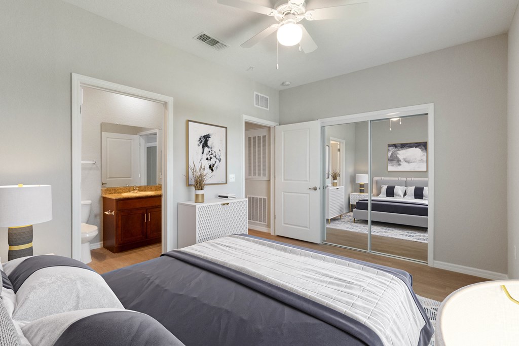 A bedroom with a bed in the foreground and a mirrored closet door.