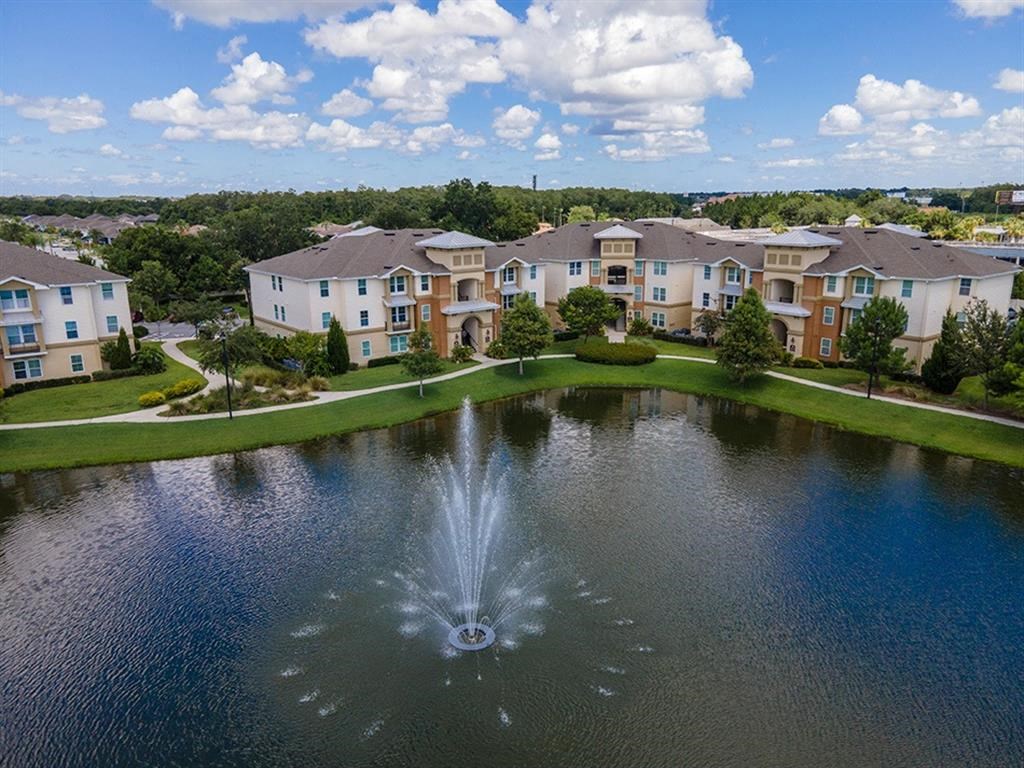 a fountain in the middle of a pond with apartment buildings in the background