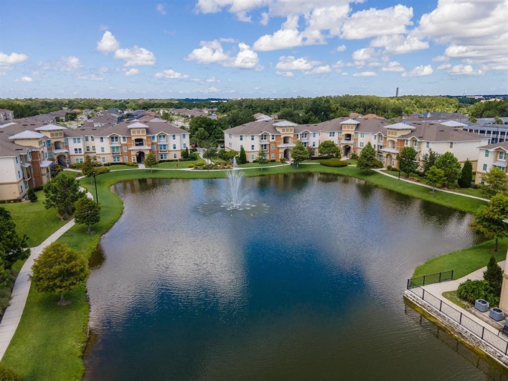 an aerial view of a pond with a fountain and apartment buildings in the background