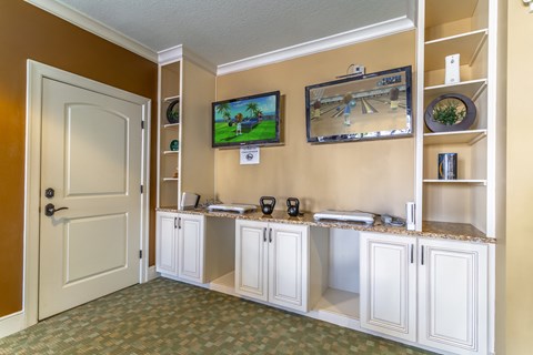 a kitchen with white cabinets and a tv on the wall
