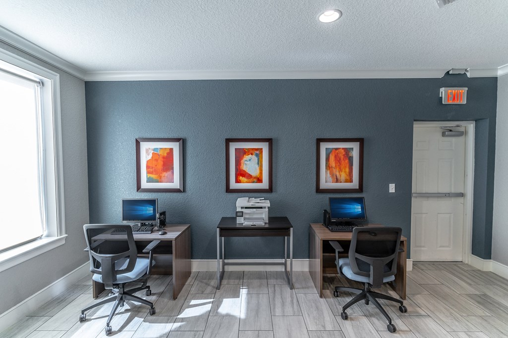 two computers and two chairs in a room with a window