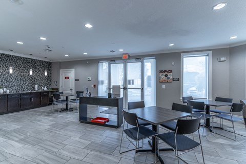 a dining room with tables and chairs and a kitchen with a counter