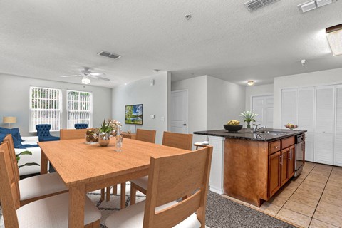 a dining area with a wooden table and chairs and a kitchen with a black counter top and