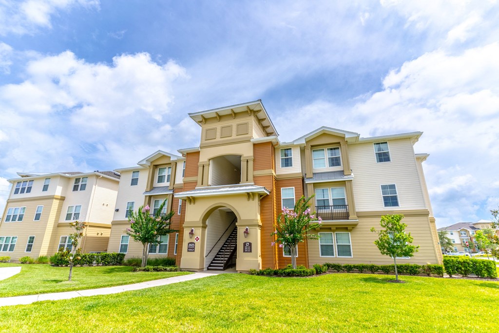 a large apartment building with a grassy area in front of it