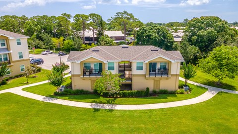 an aerial view of an apartment with a green lawn and trees in the background