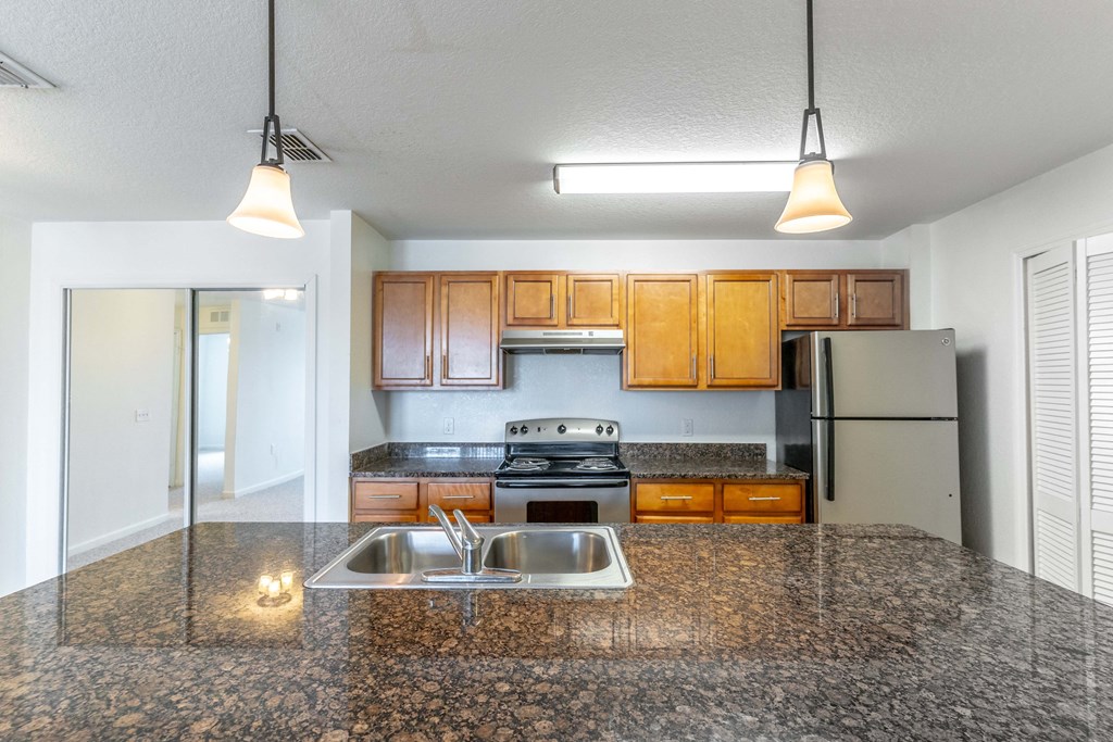 a kitchen with granite countertops and wooden cabinets