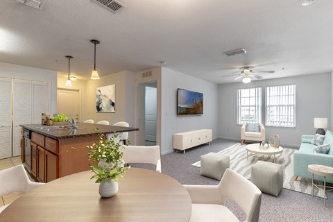 a living room with a table and chairs and a kitchen with an island