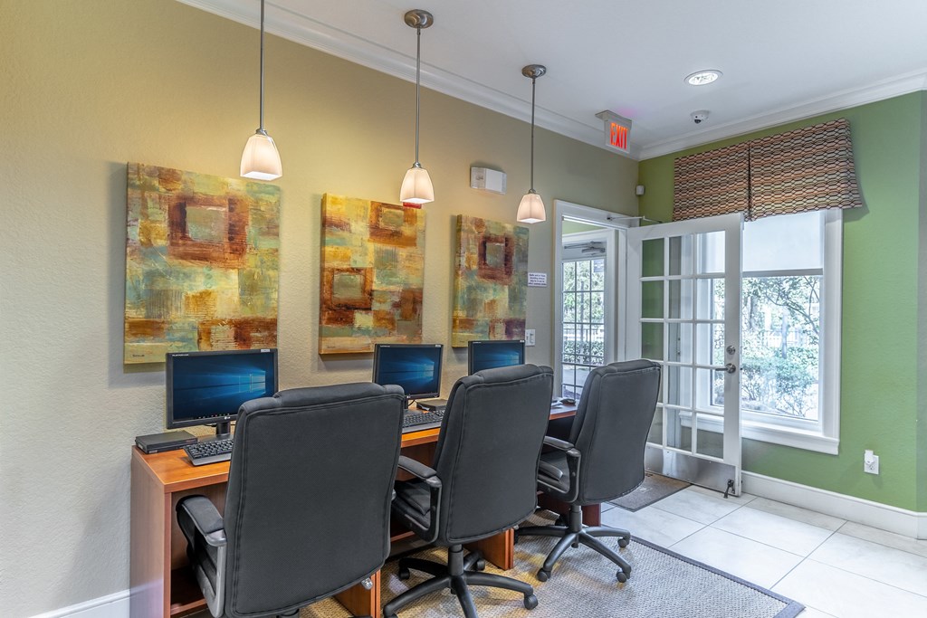 a desk with four computers in a room with green walls and a glass door