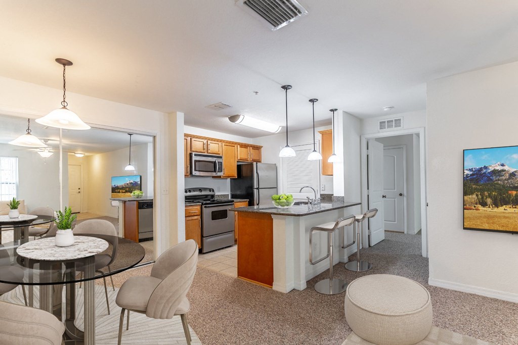 a living room with a table and chairs and a kitchen in the background
