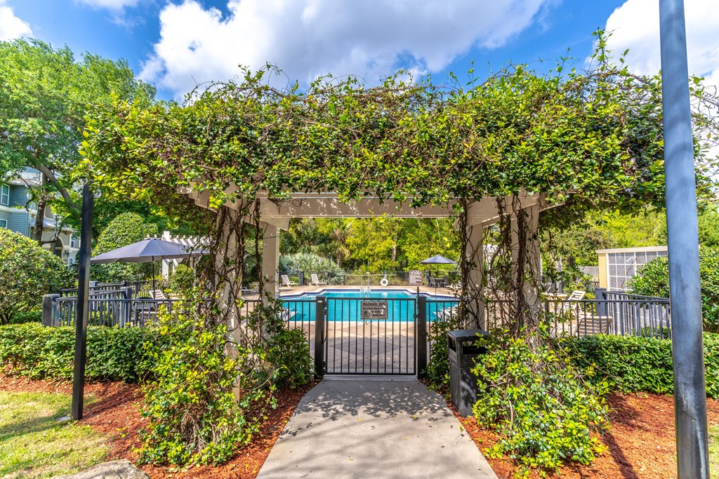a pergola with a walkway leading to a pool