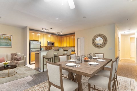 a dining room table with chairs in front of a living room and a kitchen