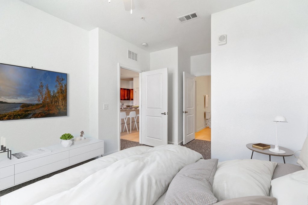 a bedroom with a large white bed and a white dresser with a potted plant