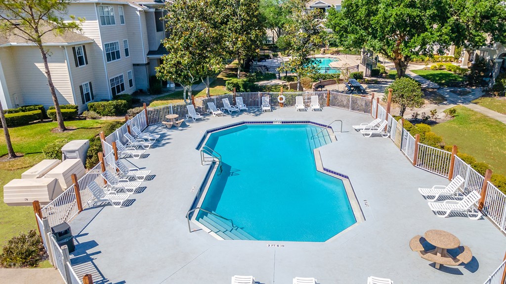 an aerial view of the resort style pool with chaise lounge chairs and trees in the background