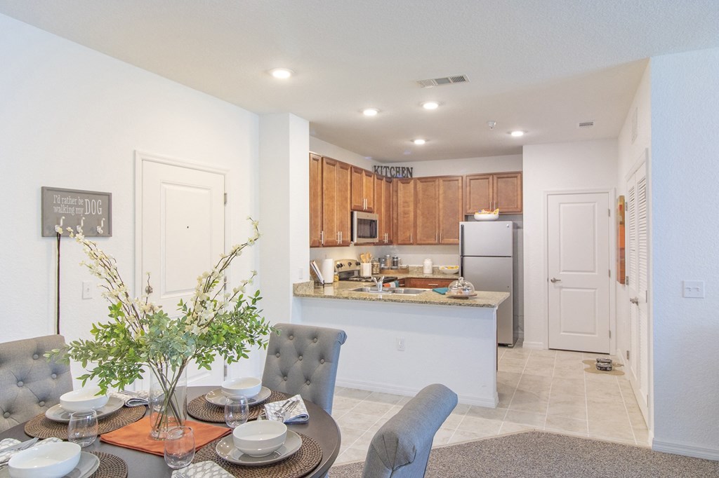 a dining area with a table and chairs and a kitchen in the background