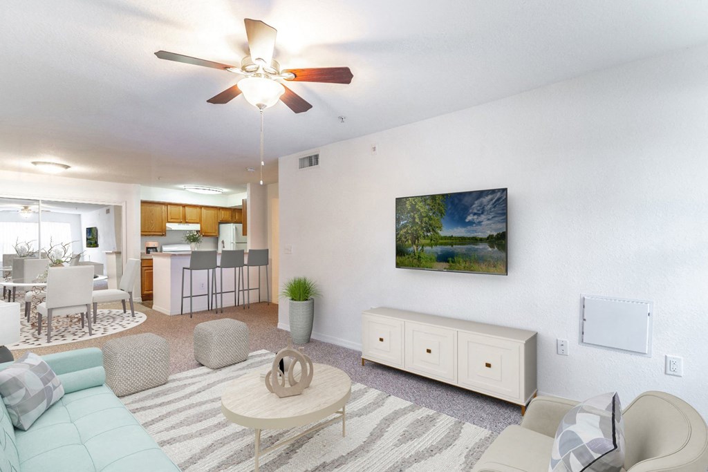 a living room with a ceiling fan and a view of the kitchen and dining area