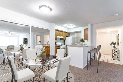 a living room with a table and chairs and a kitchen in the background