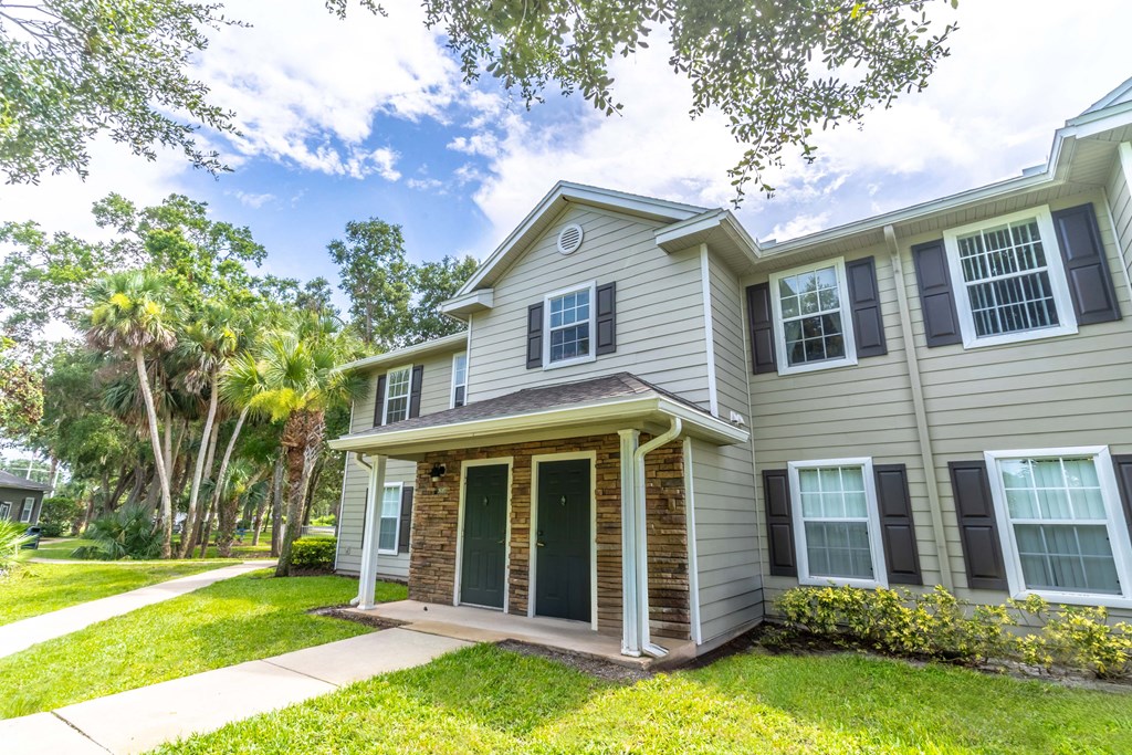 the front of a house with a lawn and palm trees