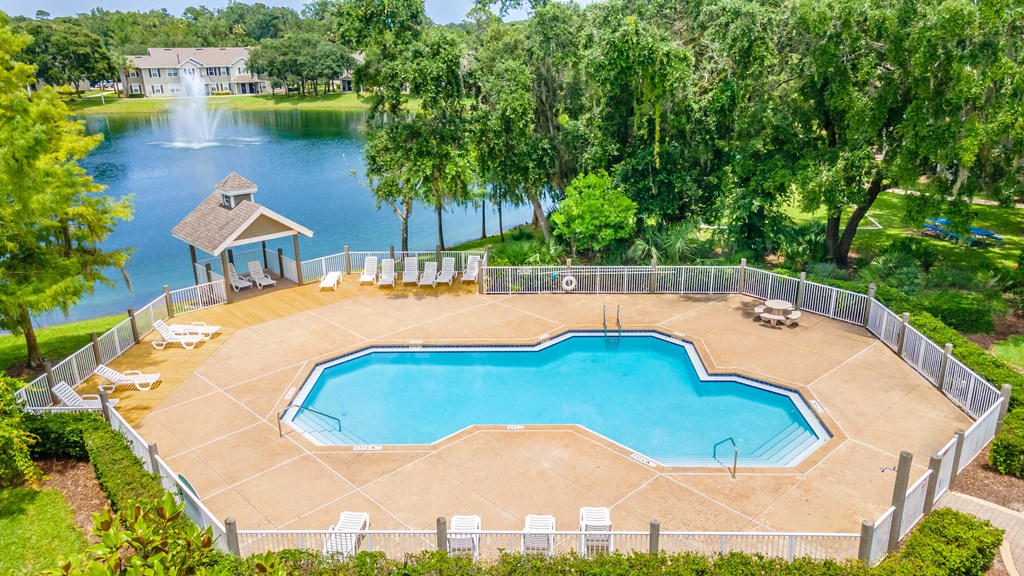 a large swimming pool with a gazebo and a lake in the background