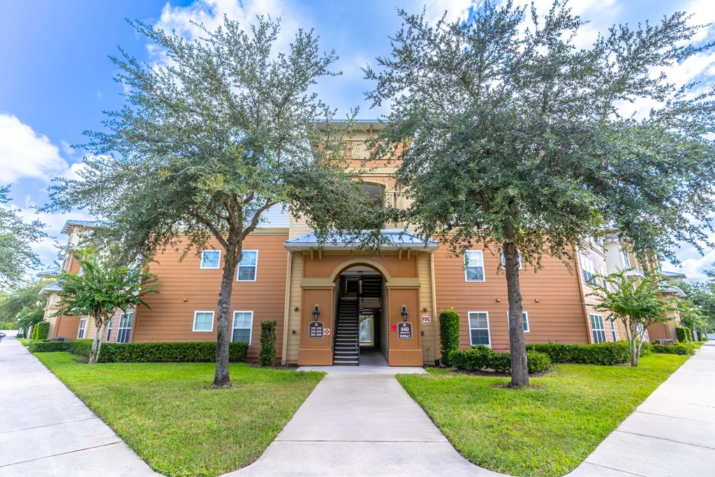 a building with a sidewalk and trees in front of it