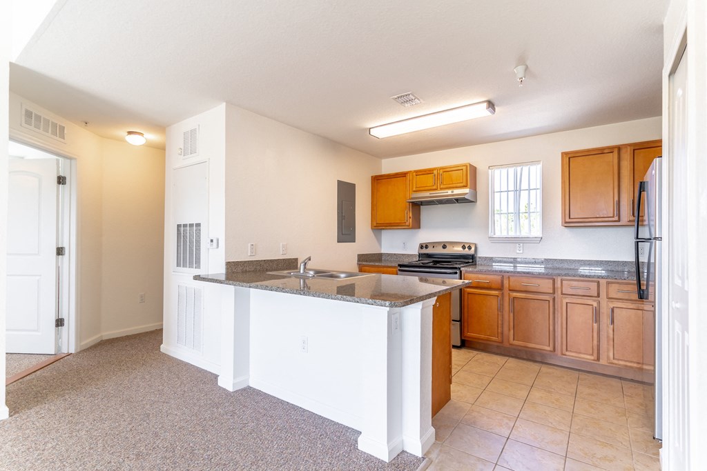 a kitchen with an island with granite countertops and wooden cabinets