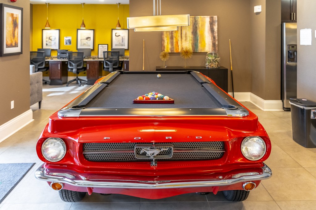 a pool table with a red car in the middle of the room