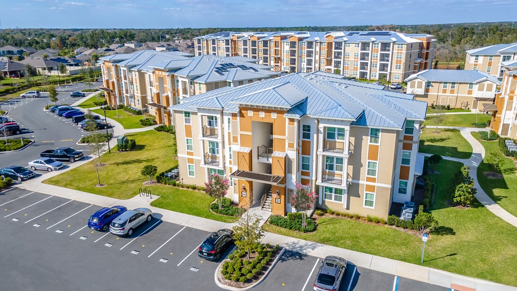 an aerial view of a large apartment complex with cars parked in front of it