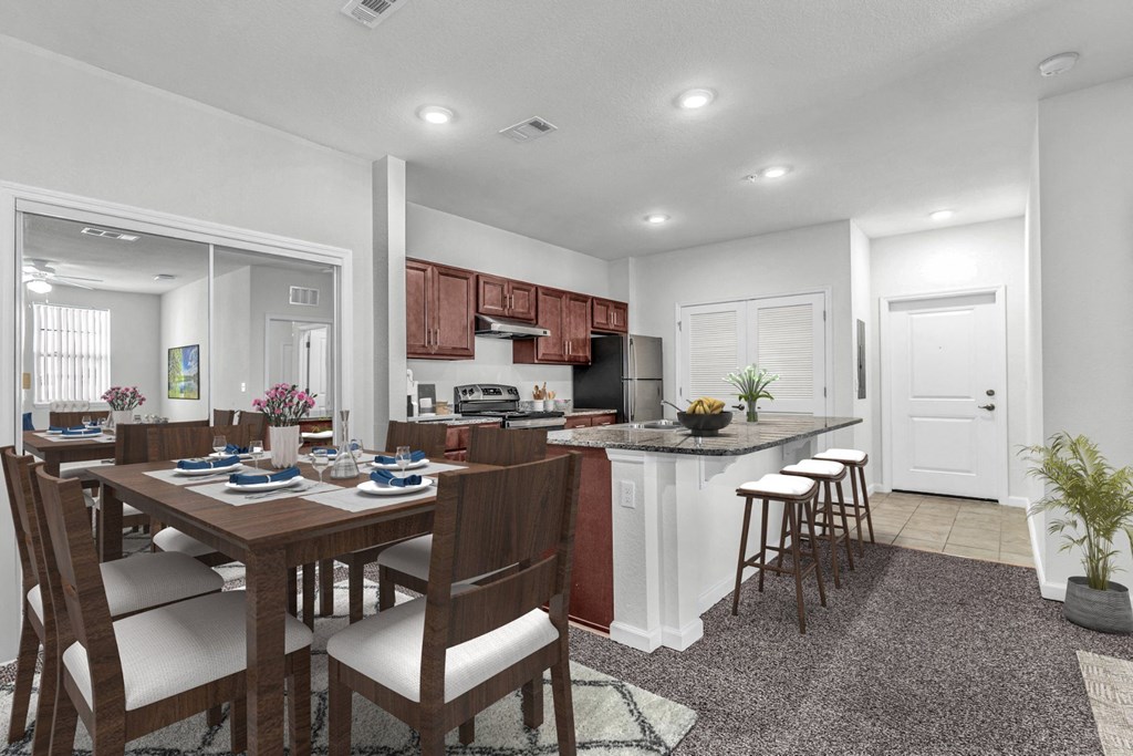 dining area with table and chairs and a kitchen with barstools and dark cabinets