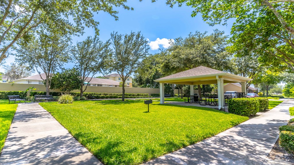 a pavilion with a picnic table and grill in the middle of a grassy area with