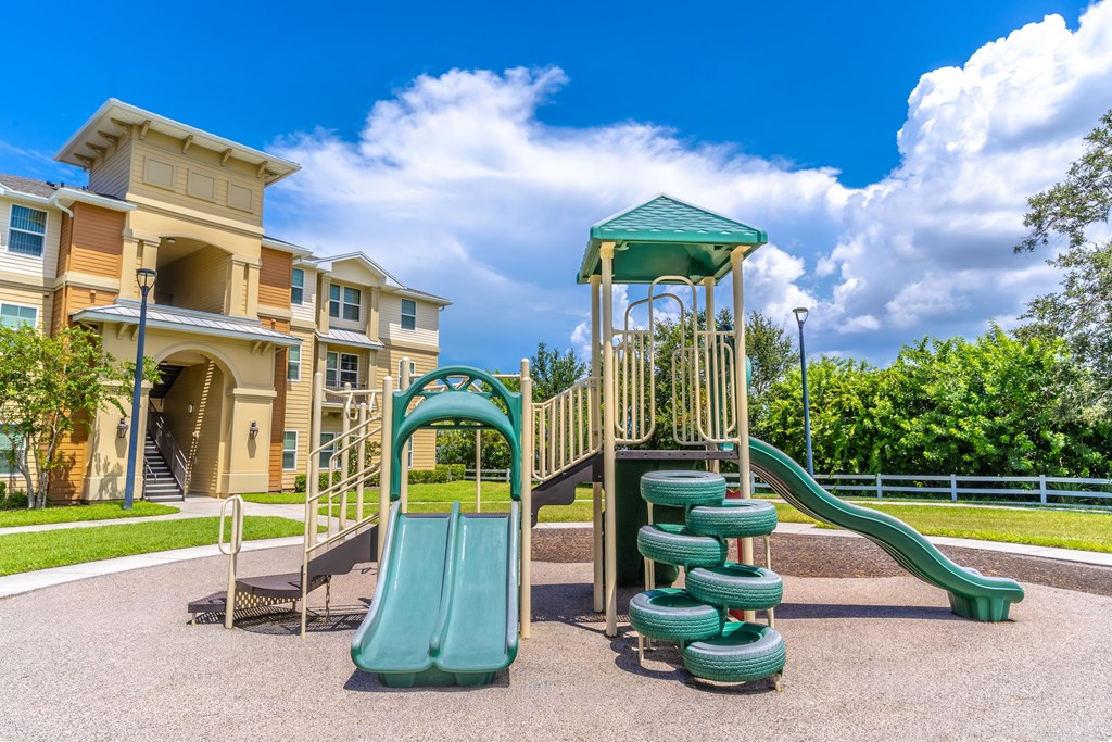 A playground with a green slide and a wooden structure.