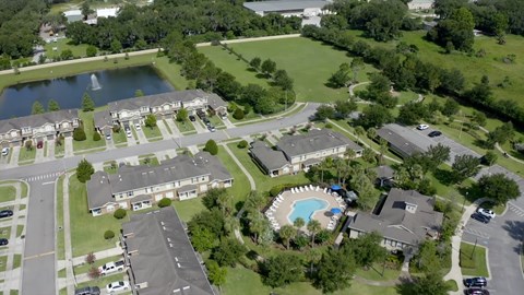 A bird's eye view of a residential area with houses, a swimming pool, and a pond.