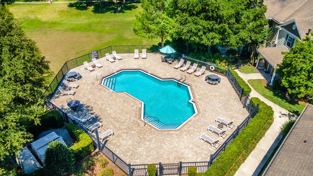 an aerial view of a large pool with lounge chairs and trees in the background