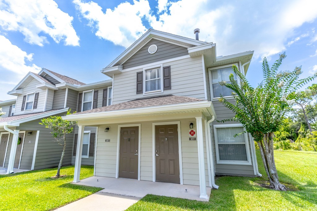 a house with gray and white siding and a green lawn