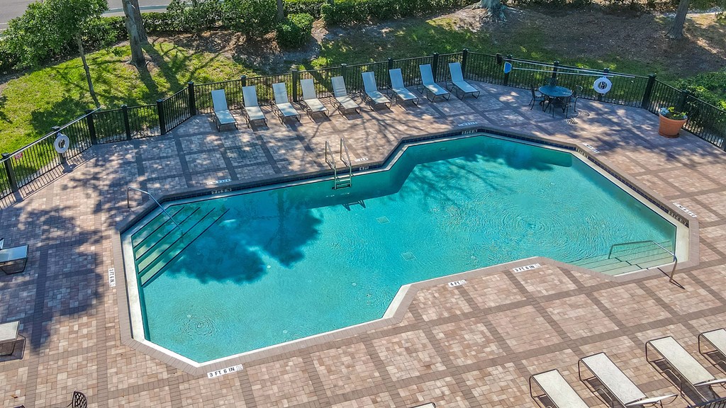 an aerial view of a resort style pool with chaise lounge chairs and trees in the background