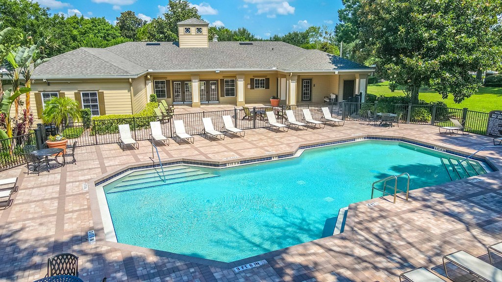 a pool with lounge chairs and a house in the background