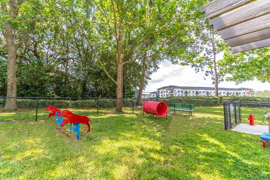 a fenced in dog park with a red fire hydrant and a blue bench