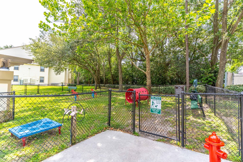 a fenced in dog park with a red fire hydrant and a blue bench