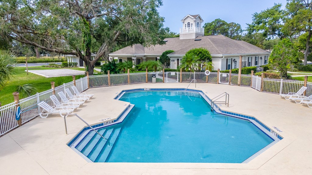 a swimming pool with chaise lounge chairs and a house in the background