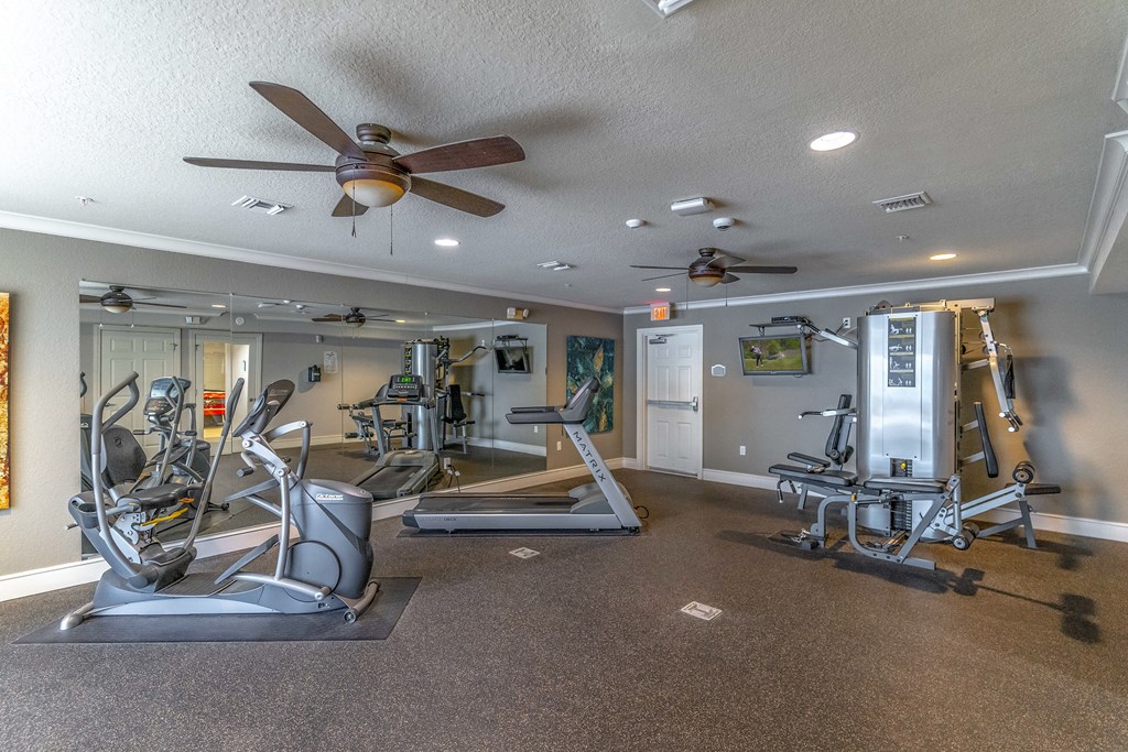a gym with exercise equipment and a ceiling fan