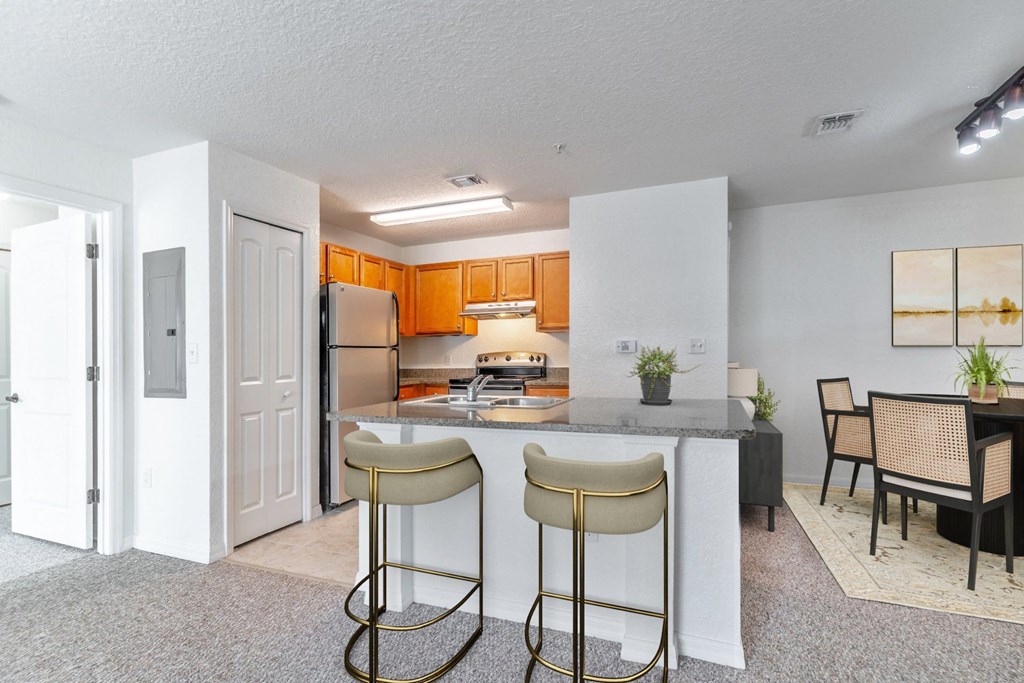 a kitchen with a breakfast bar and a dining room in the background