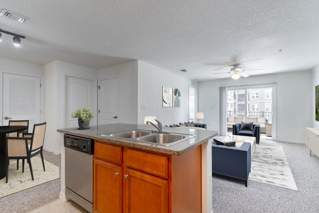 a kitchen with an island and a living room in the background