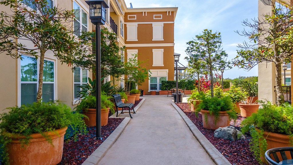 a walkway with benches and potted plants in front of a building