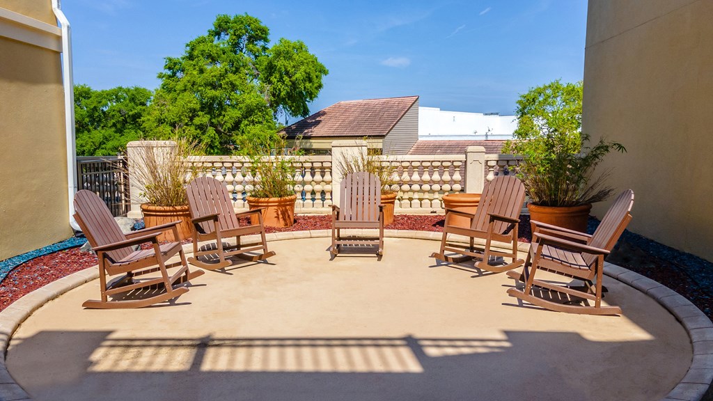 a circular patio with adirondack chairs and potted plants