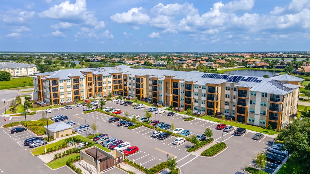 an aerial view of a large apartment complex with a parking lot and a lake in the background